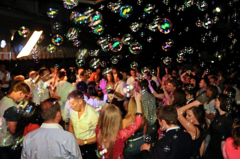 people dancing on a party with many soap bubbles